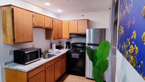 Une cuisine de taille réduite, dotée de meubles en bois, d’un four à micro-ondes, d’une cuisinière et d’un réfrigérateur.