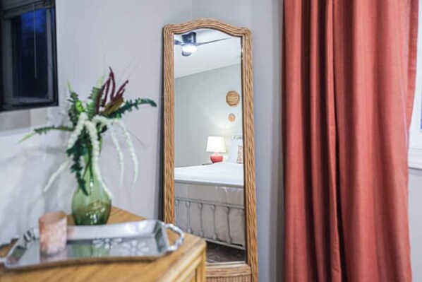 A room with a wooden dresser, a mirror, a green vase, and a red curtain. - Perfect for Groups! Near Forsyth w/Yard & Parking! (Savannah)