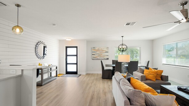A modern living room with a sofa, a dining area, and a kitchen.