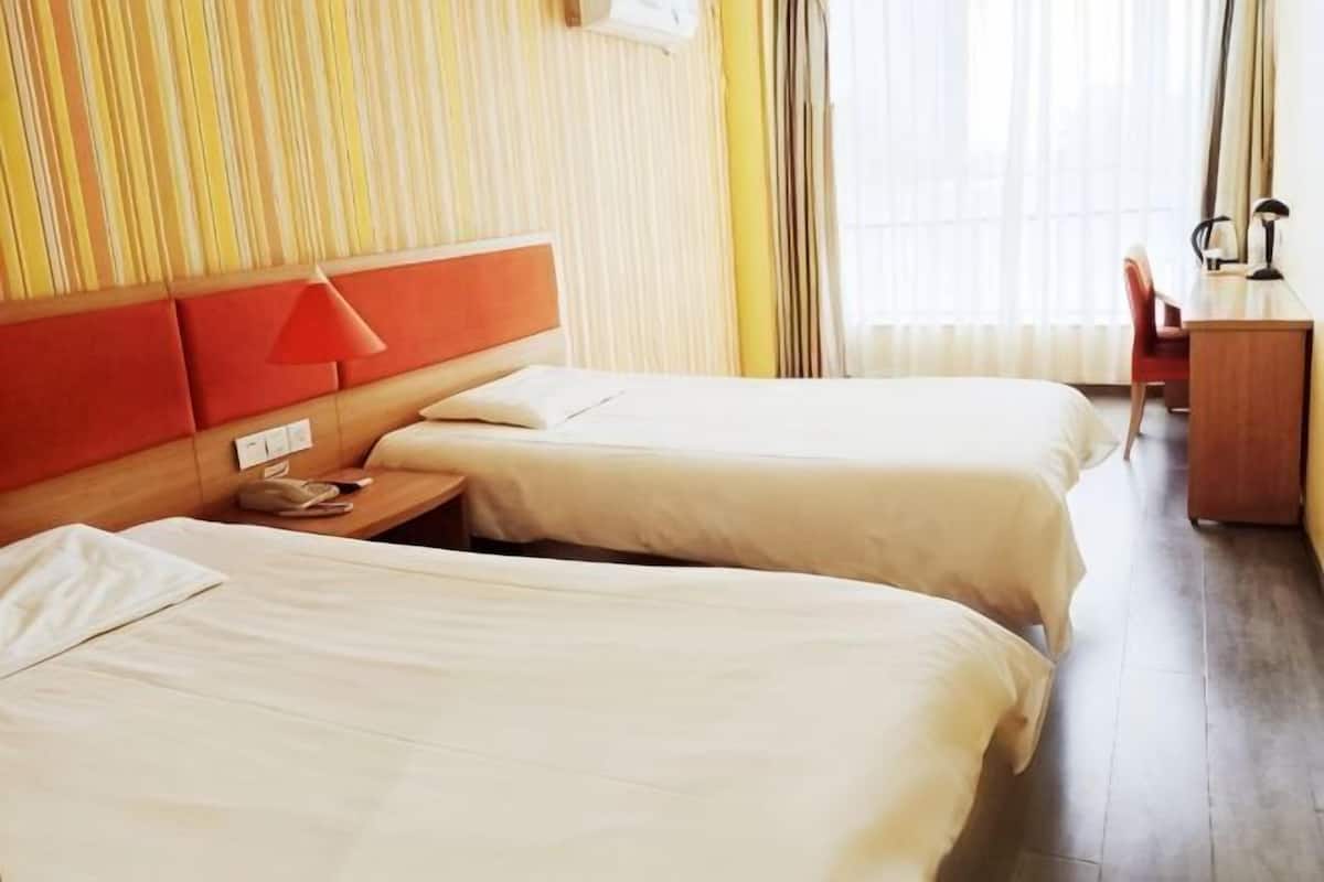 A hotel room with two beds, a desk, and a chair.