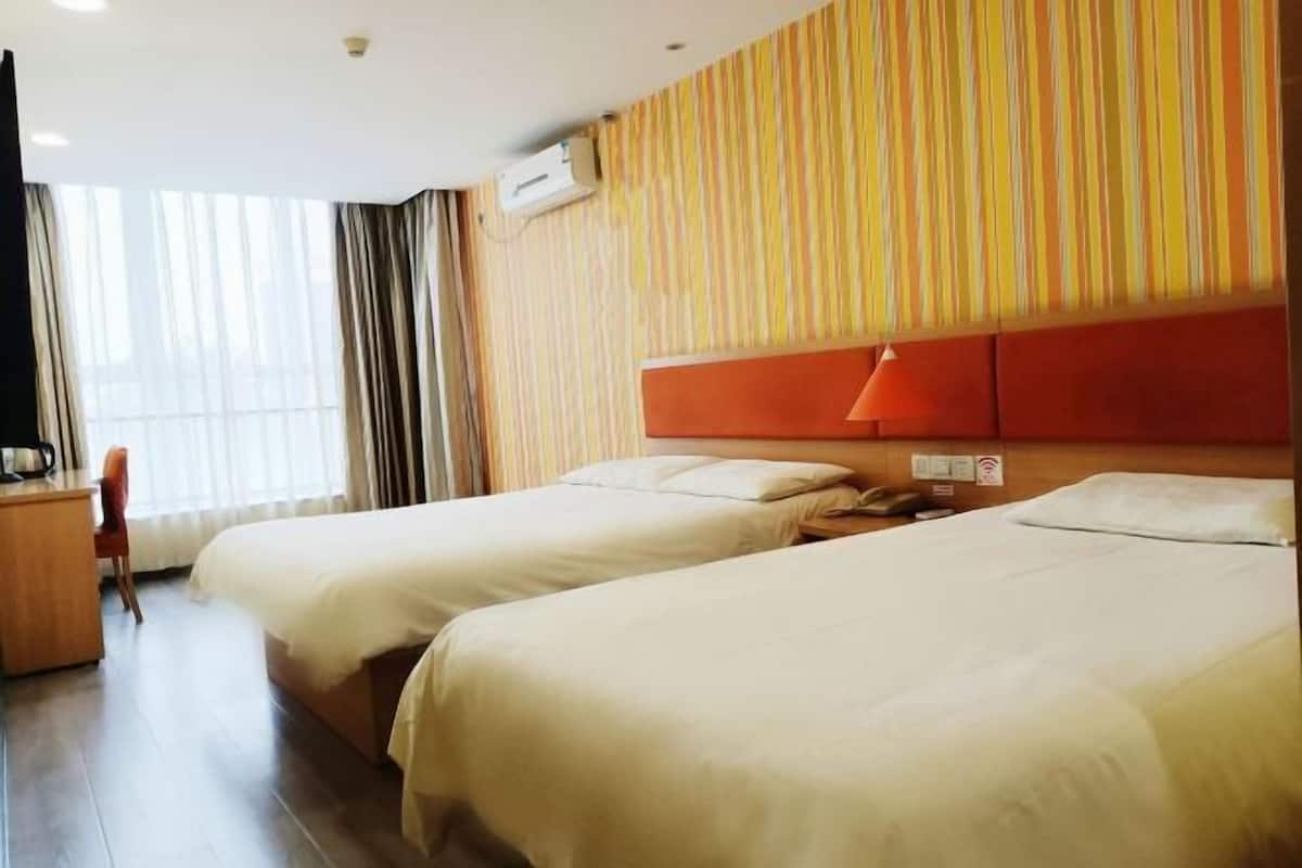 A hotel room with two beds, a desk, a chair, and a window with curtains.
