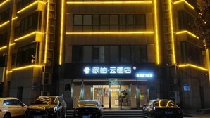 A hotel facade with illuminated vertical lines and a sign in a foreign language. - Homeinn Pebble Hotel (Linyi Yinan Government Plaza) (Yinan)