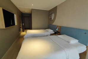 A hotel room with two beds, a TV mounted on the wall, and a door leading to another room.