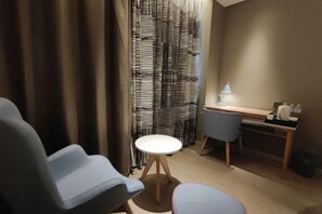 A room with a desk, two chairs, a small round table, and a curtain with a geometric pattern. - Homeinn Pebble Hotel (Linyi Yinan Government Plaza) (Yinan)