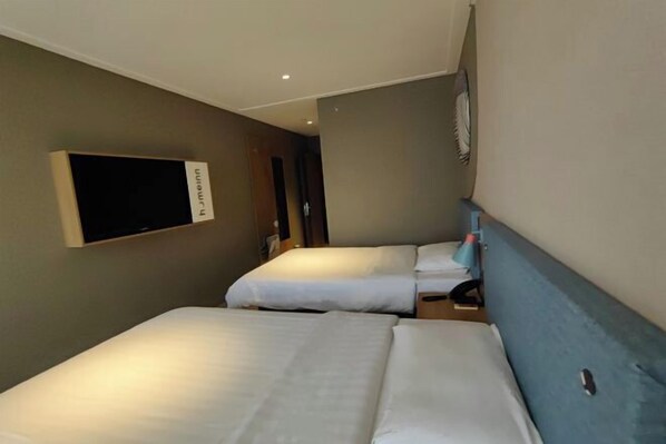 A hotel room with two beds, a flat-screen TV mounted on the wall, and a small table with a chair. - Homeinn Pebble Hotel (Linyi Yinan Government Plaza) (Yinan)