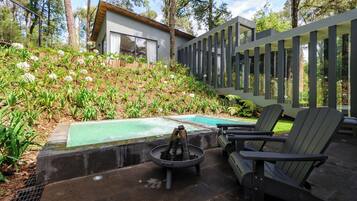 A modern outdoor patio with a fire pit, seating area, and a swimming pool.