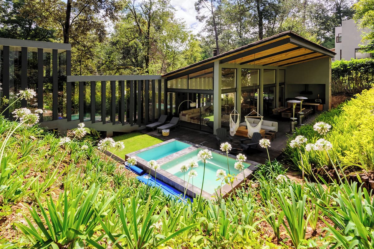 A modern house with a pool, outdoor seating, and lush greenery.
