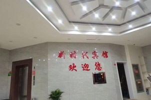 A hotel reception area with a tiled wall and a sign in a foreign language.