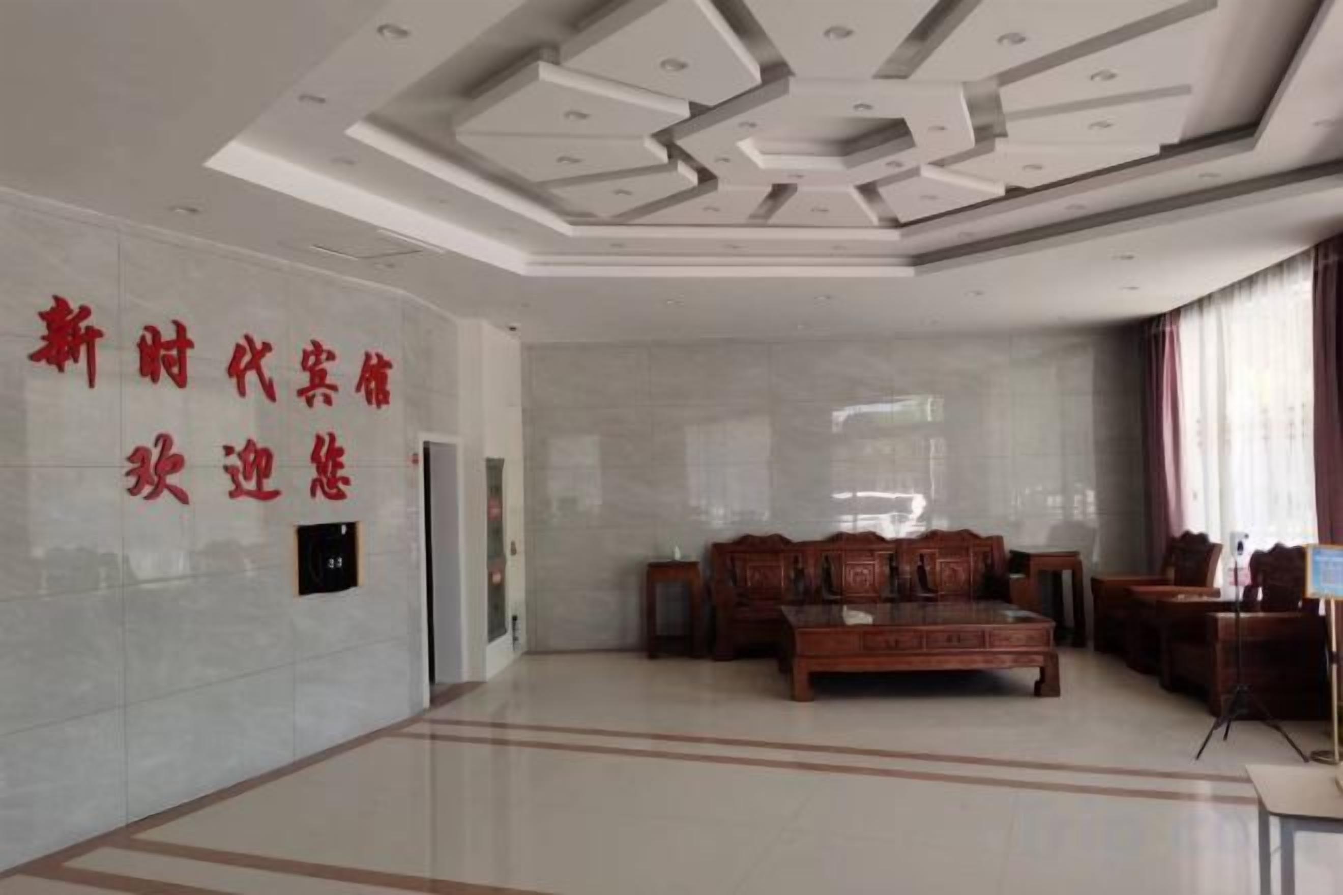 A hotel lobby with a reception desk, a seating area with chairs, and a wall with text.