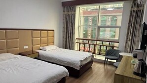 Habitación de hotel con dos camas, un escritorio, una silla y un ventanal con vistas a edificios.