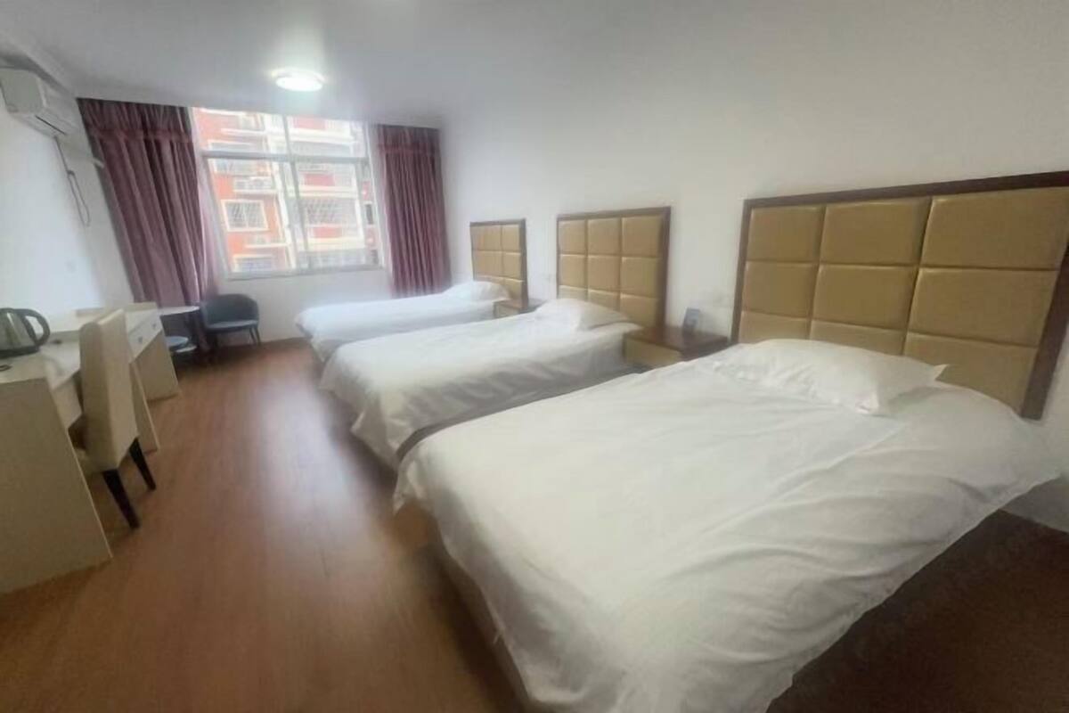 A hotel room with two beds, a desk, a chair, and a window with curtains.