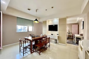 Una cocina moderna con una mesa de comedor y sillas, un televisor montado en la pared y una ventana que proporciona luz natural.