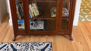 A wooden bookcase with glass doors, filled with books and magazines. - Charming 3-bedroom cottage in Hampden with AC, WiFi (Hampden)