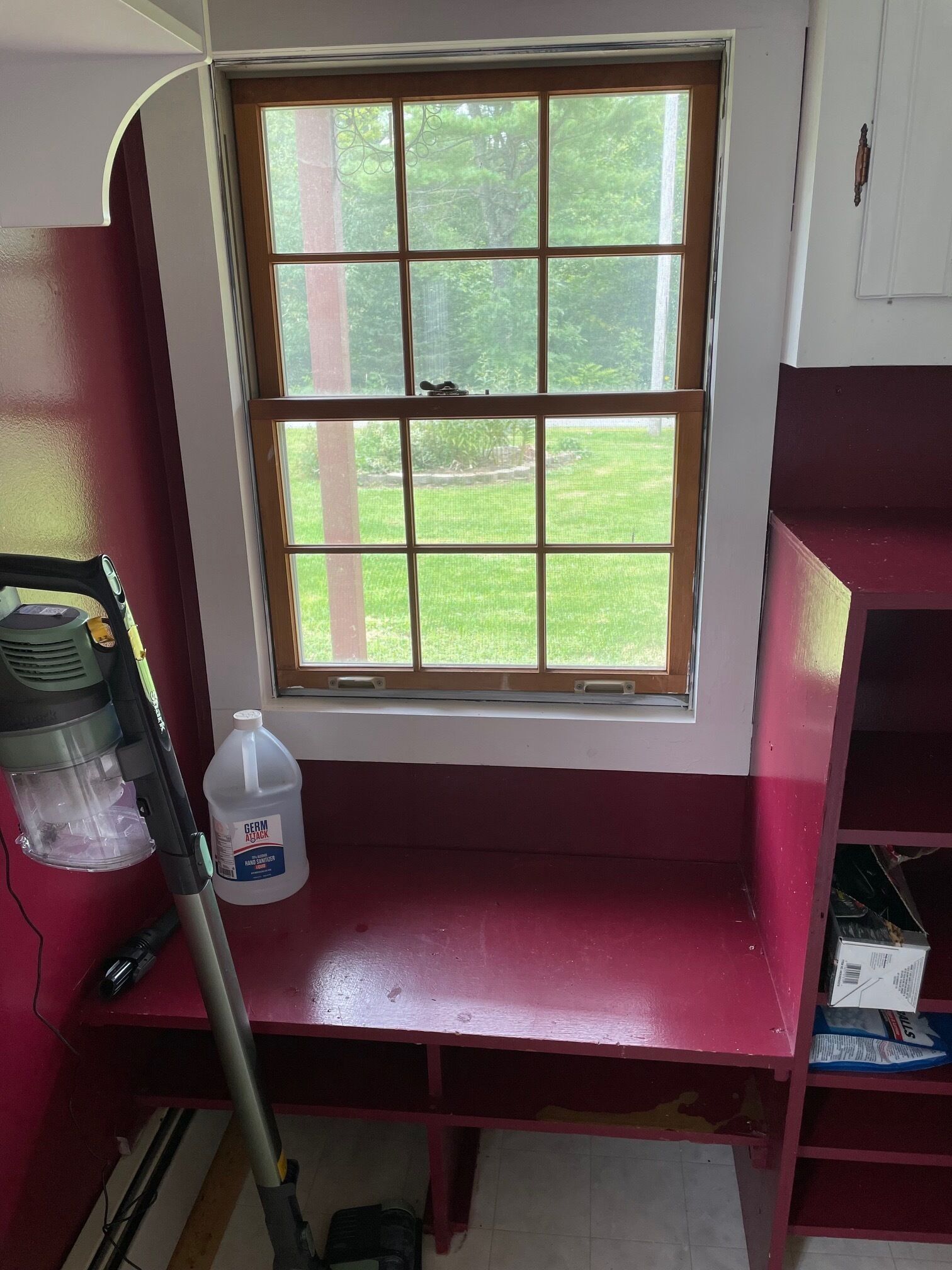 A room with a window, a vacuum cleaner, and a bottle of hand sanitizer.