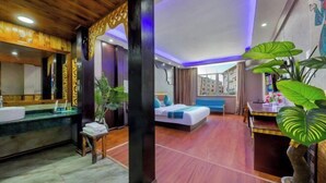 A hotel room with a wooden ceiling, a large bed, a sitting area with a table and chairs, and a bathroom with a sink and mirror. - Xishuangbanna Peacock Princess Hotel (Jinghong)