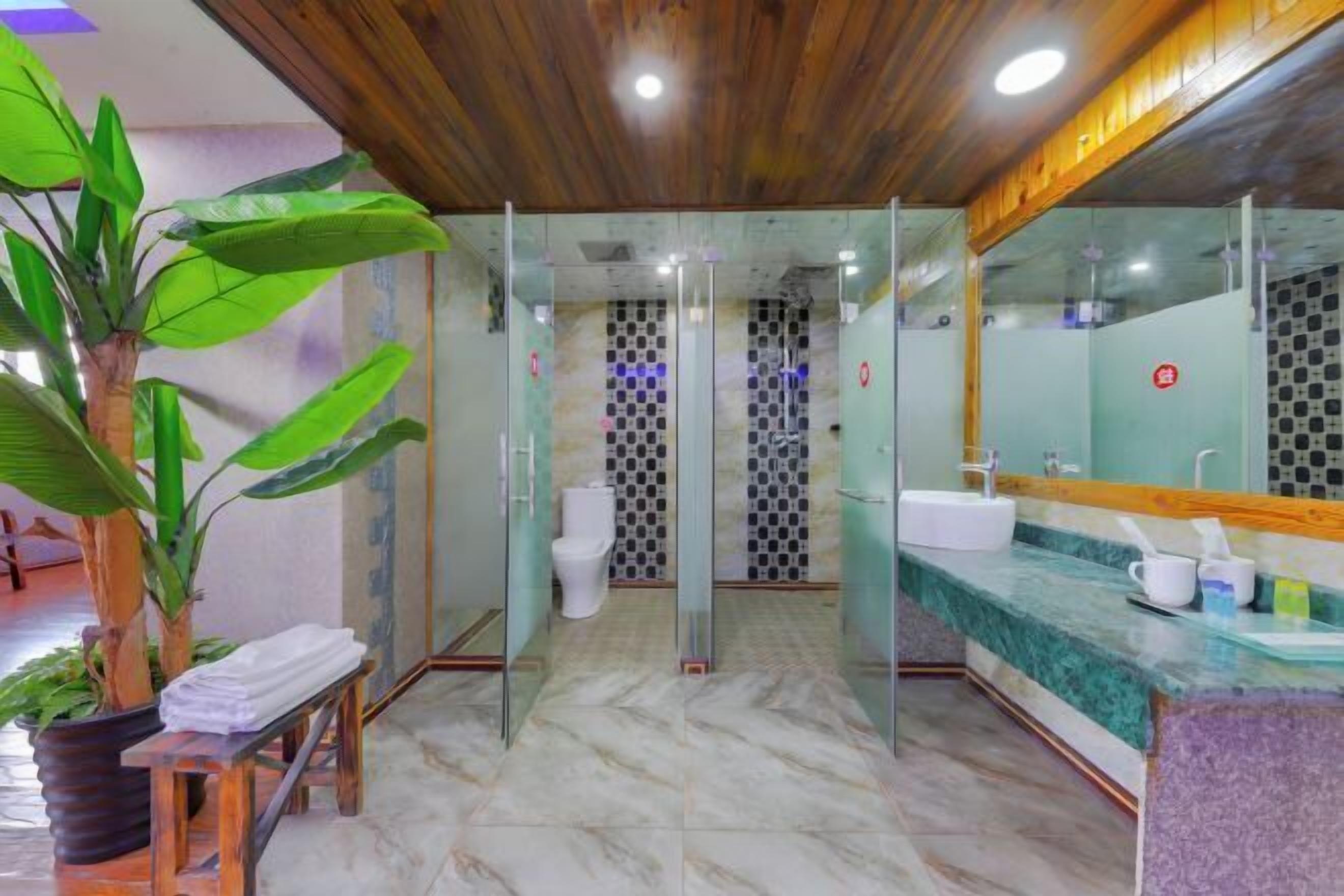 A modern bathroom with glass shower doors, a marble floor, and a wooden ceiling.
