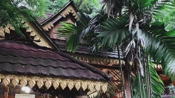 A traditional wooden structure with intricate carvings, surrounded by lush greenery. - Xishuangbanna Peacock Princess Hotel (Jinghong)
