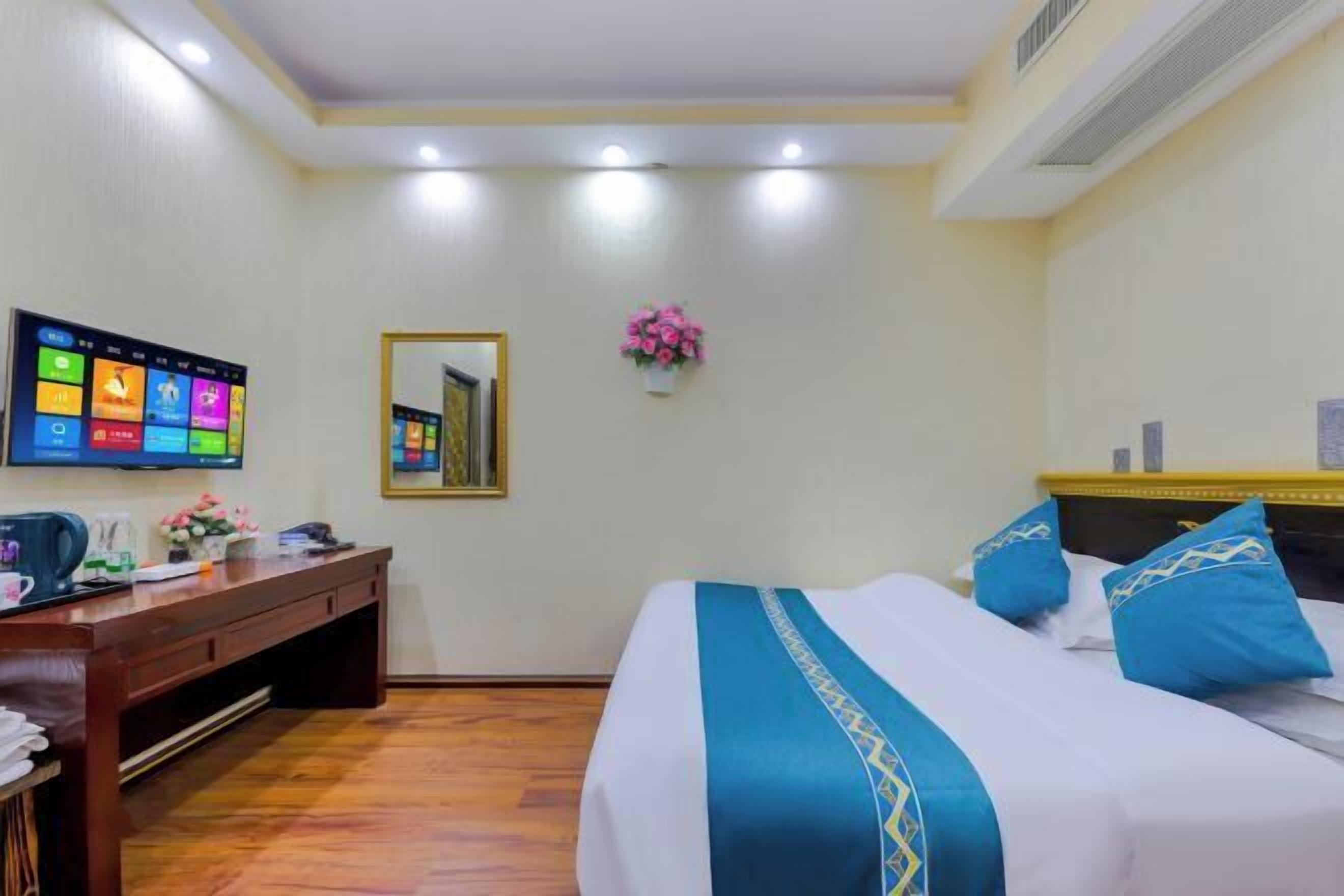 Een hotelkamer met een bed, een bureau, een flatscreen televisie en een spiegel.