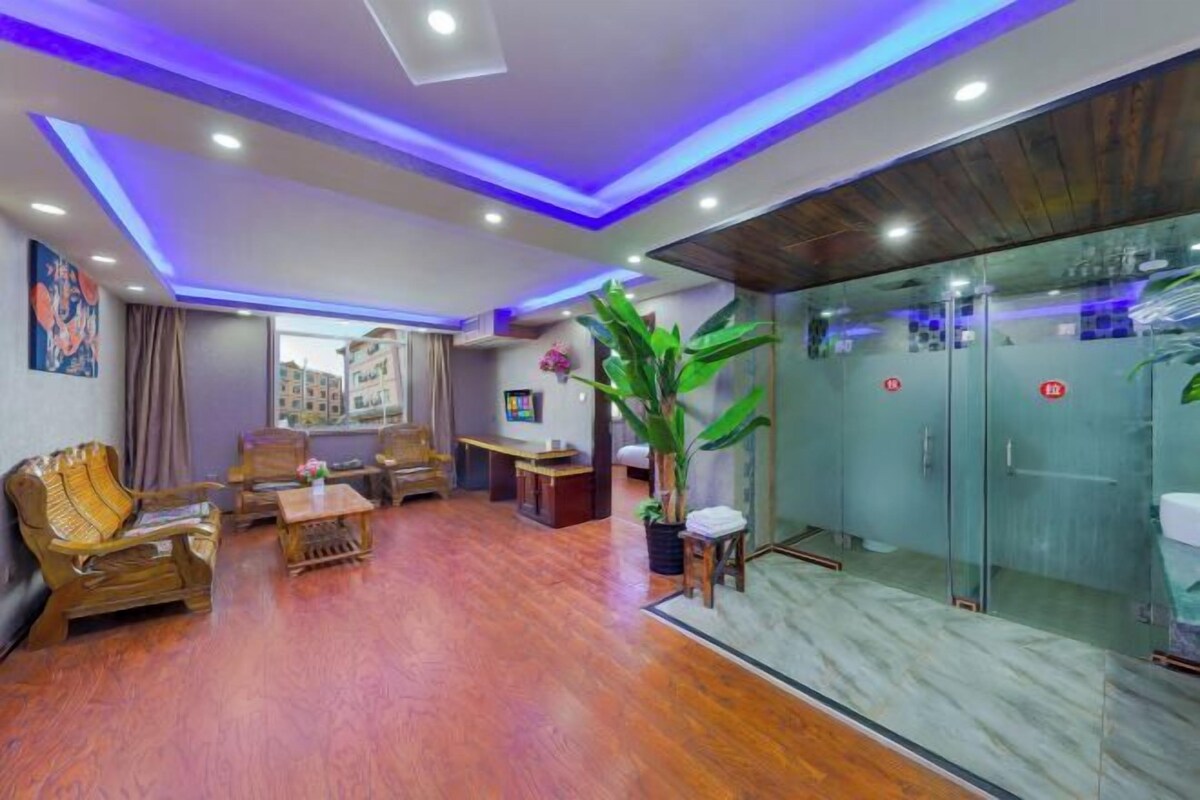 A modern living room with wooden furniture, a glass partition, and a large potted plant.