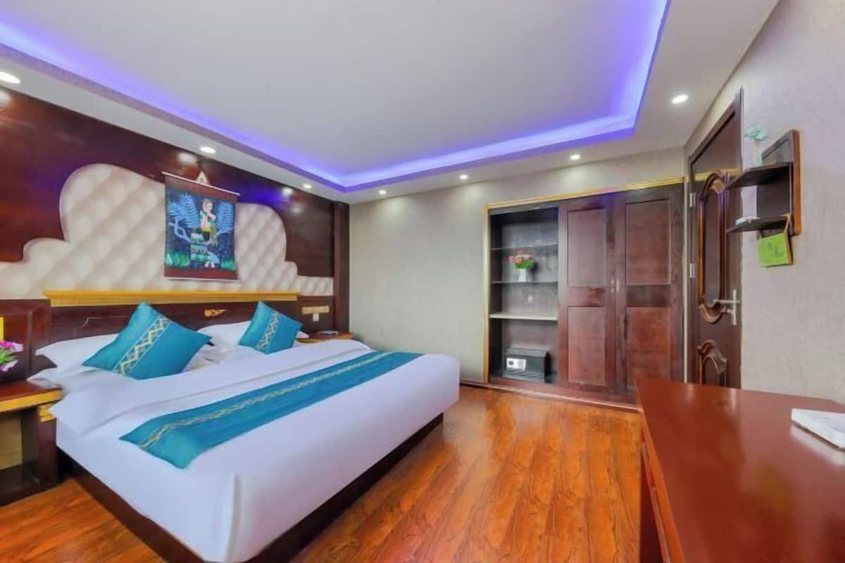 Ein Hotelzimmer mit einem Bett, Holzboden, einem Schreibtisch, einem Kleiderschrank und einer Wand mit dekorativer Verkleidung.
