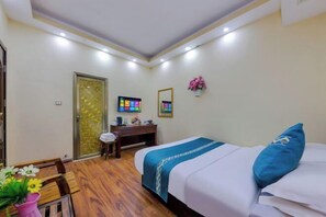 A hotel room with a bed, a desk, a chair, a TV, and a door. - Xishuangbanna Peacock Princess Hotel (Jinghong)