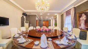 A formal dining room with a round table, chairs, and a chandelier.