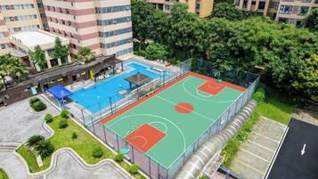 An outdoor basketball court surrounded by trees and buildings.