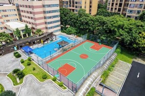 En utomhusbasketplan omgiven av träd och byggnader.