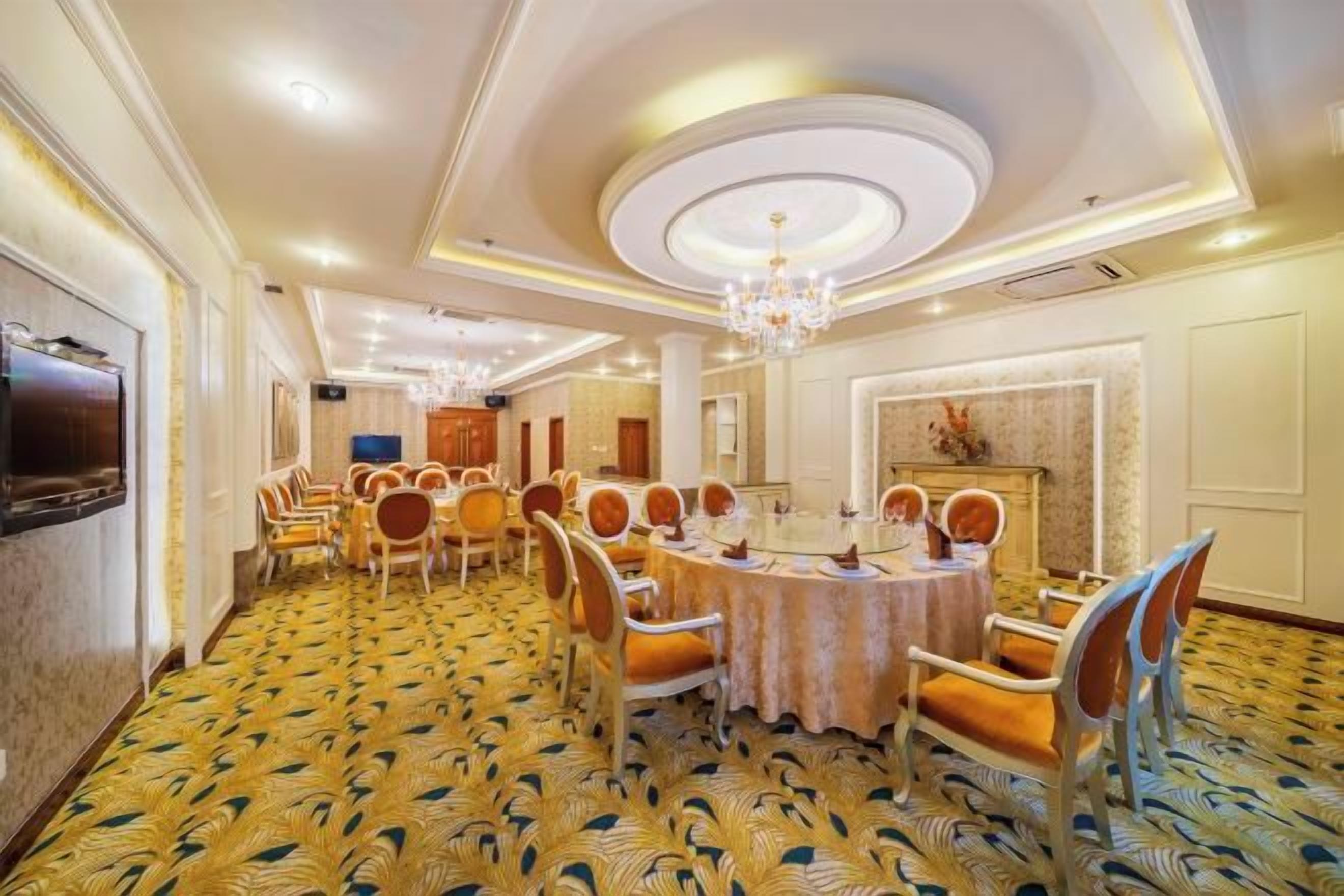Un comedor de hotel con mesas redondas, sillas y un candelabro.