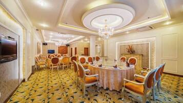 Un comedor de hotel con mesas redondas, sillas y un candelabro.