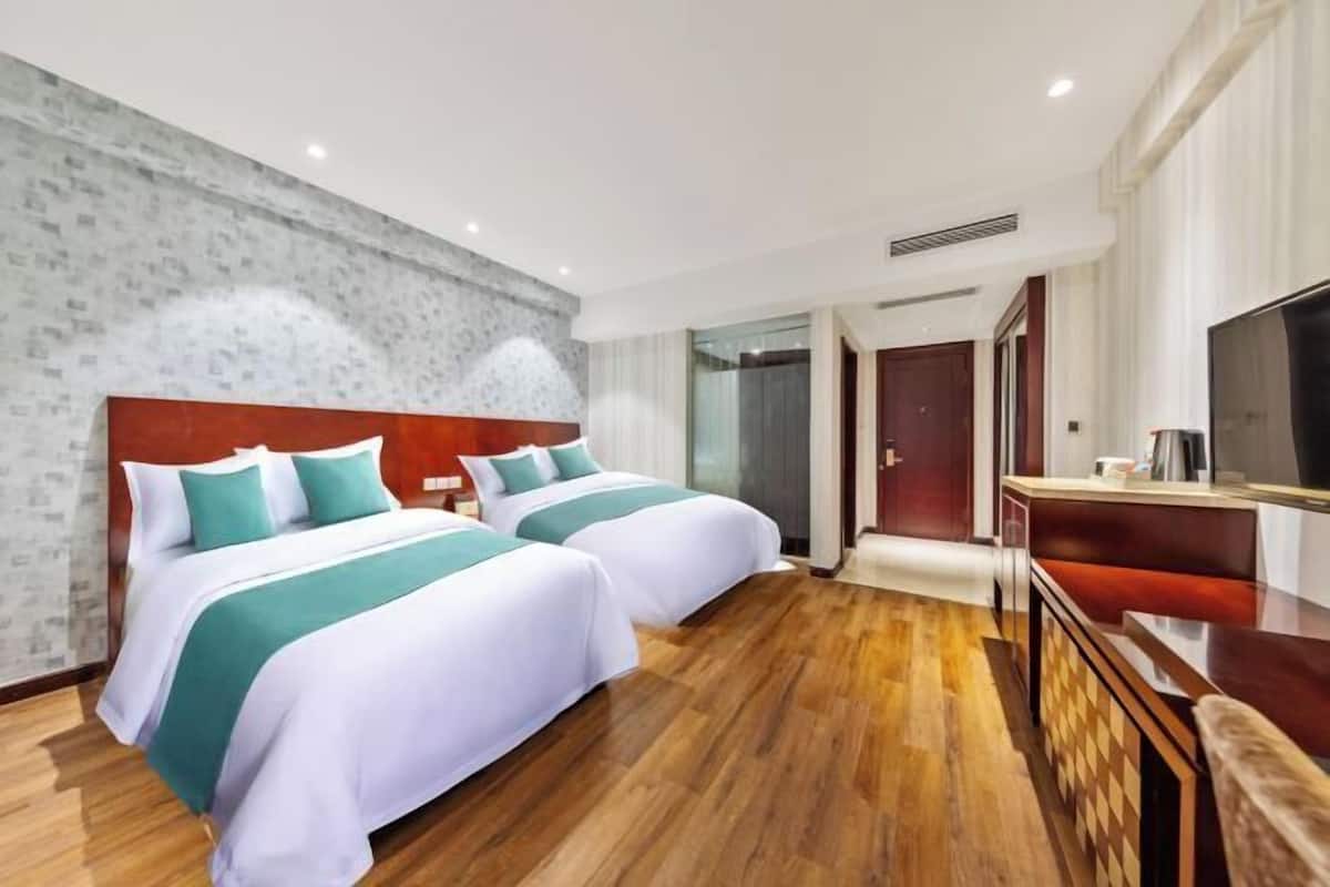 A hotel room with two beds, a TV, a wooden floor, and a modern design.