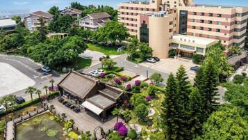 A hotel with multiple floors, a courtyard with a fountain, and surrounding greenery.