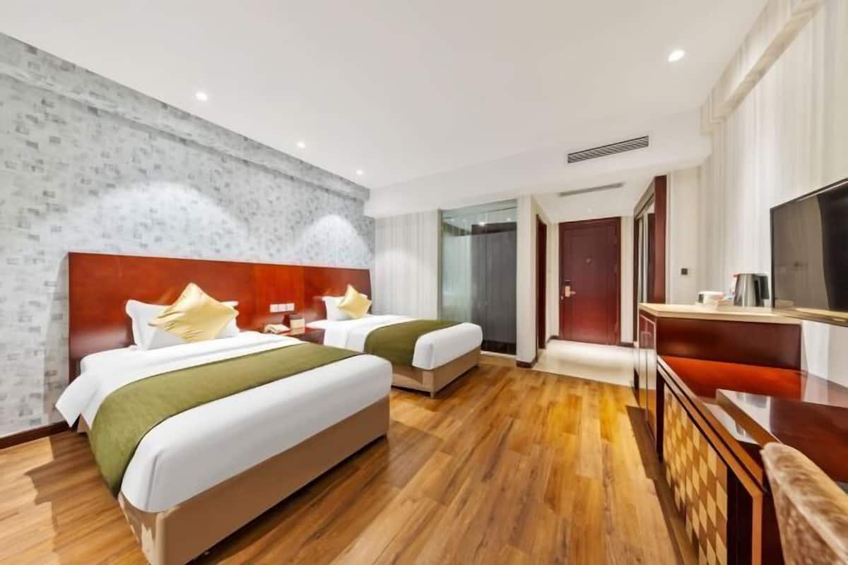 A hotel room with two beds, a TV, a desk, and a bathroom.