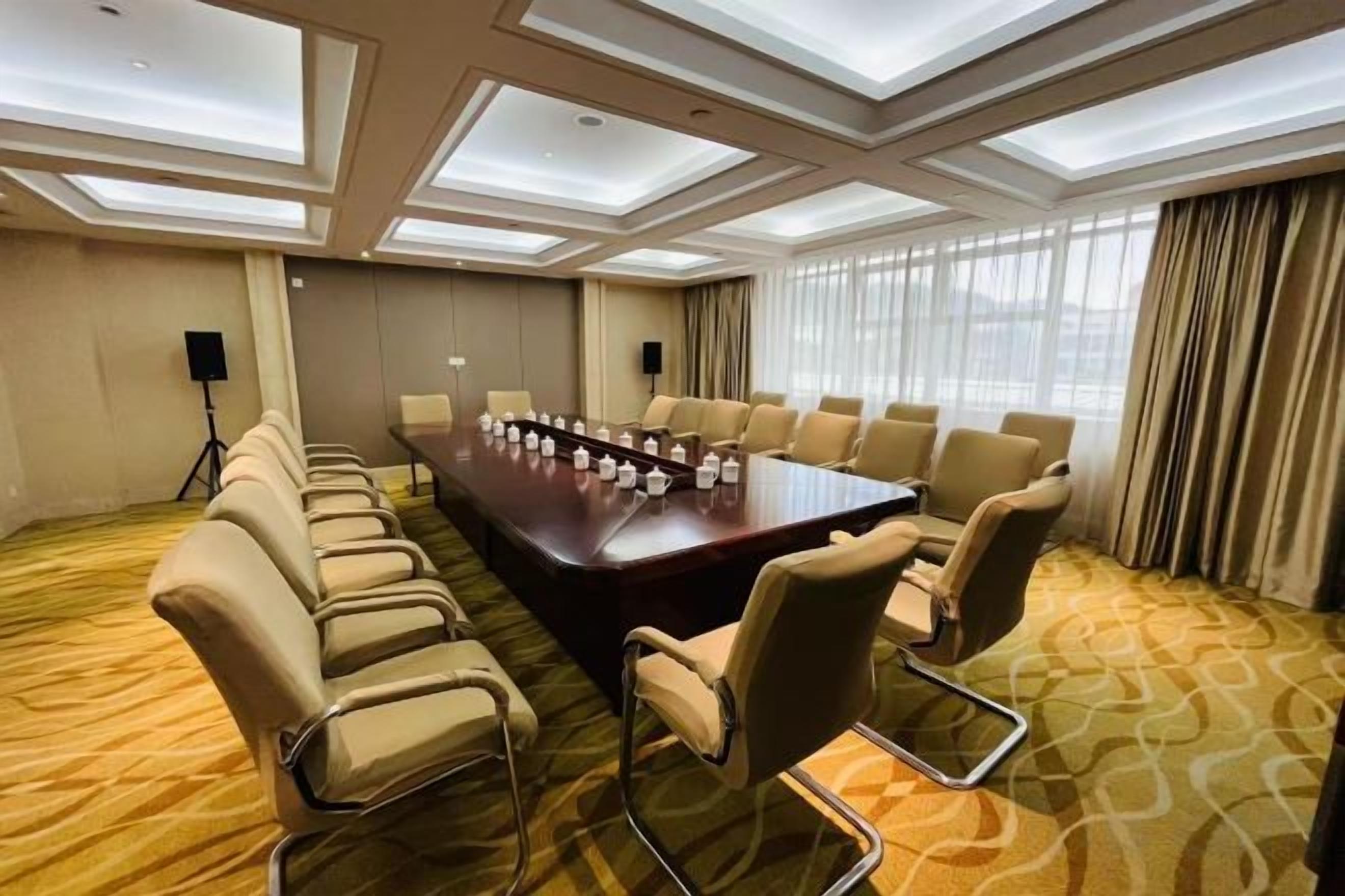 Un salón de conferencias con una larga mesa, sillas y un proyector.