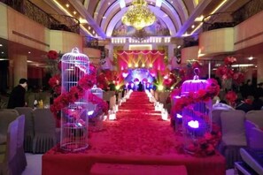A banquet hall with a red carpet aisle, floral decorations, and a chandelier. - Chengdu Star Flower Garden Hotel (University Games Sports Center) (Chengdu)