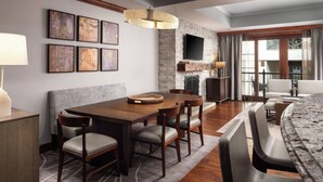 A modern dining area with a wooden table and chairs, a fireplace, and a television mounted on the wall. - The Ritz-Carlton Club®, Vail, Colorado. 2 Bedroom + DEN. 8PAX (Vail)