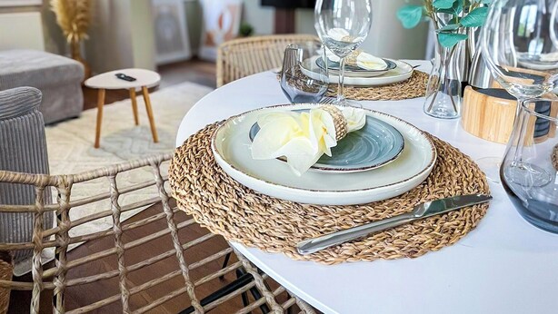 A dining area with a round table set for two, featuring woven placemats and a candle holder. - Secretapartment: Zentral und Gemütlich, mit Großem Balkon (Warburg)