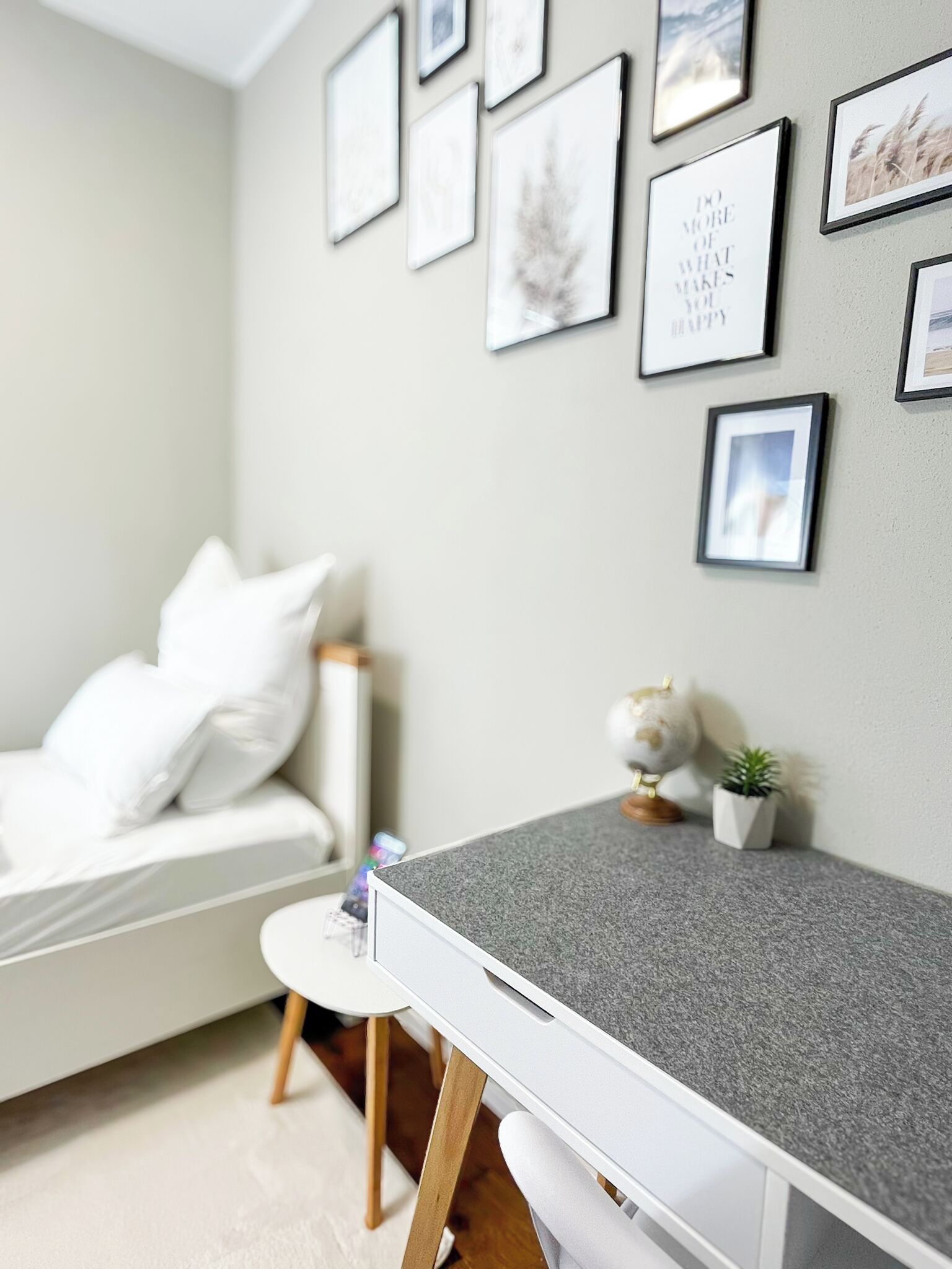Une chambre moderne avec un lit, un bureau et un mur décoré de tableaux encadrés.