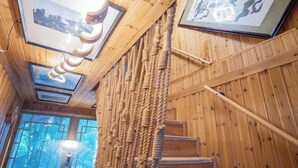 Un intérieur en bois agrémenté d’un mur décoré de cordes, de tableaux encadrés et d’un escalier.