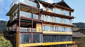Un immeuble en bois à plusieurs étages, doté de balcons et de grandes fenêtres, qui ressemble probablement à un hôtel ou à une maison d’hôtes.