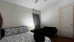 Ein Schlafzimmer mit Bett, Stuhl, Tür und Deckenventilator.