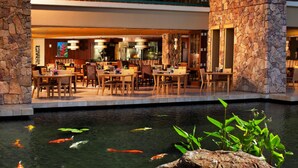 A restaurant with outdoor seating, stone walls, and a koi pond. - Ocean View-1Bdrm:1Bath -Westin Kaanapali Maui North Villas (Lahaina)