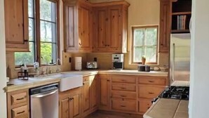 A kitchen with wooden cabinets, a dishwasher, a stove, and a refrigerator. - Peaceful spacious Spanish style Casita in Wine Country (Santa Ynez)