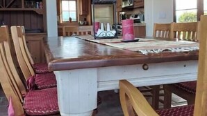 A dining area with a wooden table and chairs, a potted plant, and a kitchen in the background. - Peaceful spacious Spanish style Casita in Wine Country (Santa Ynez)