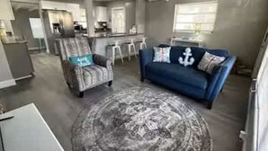 A living room with a blue sofa, patterned armchair, and a round rug.
