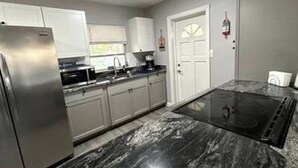 A modern kitchen with stainless steel appliances, a granite countertop, and a black induction cooktop.