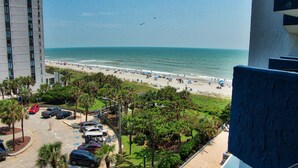 Vista de una playa con un área de estacionamiento y un edificio al frente.