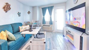 Una sala de estar con un sofá azul, una mesa de centro, un televisor y una chimenea.