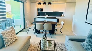 Een moderne woonkamer met een bank, salontafel en een eethoek met stoelen en een tafel.