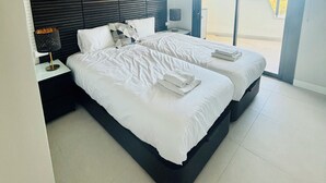 Een moderne hotelkamer met twee bedden, een groot raam en een wand bekleed met donker hout.